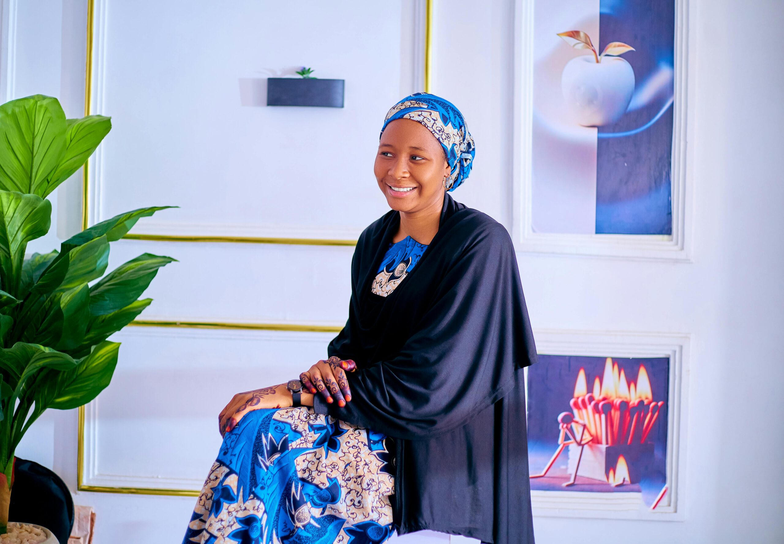 Elegant Nigerian woman in traditional attire sitting indoors, showcasing vibrant cultural fashion.